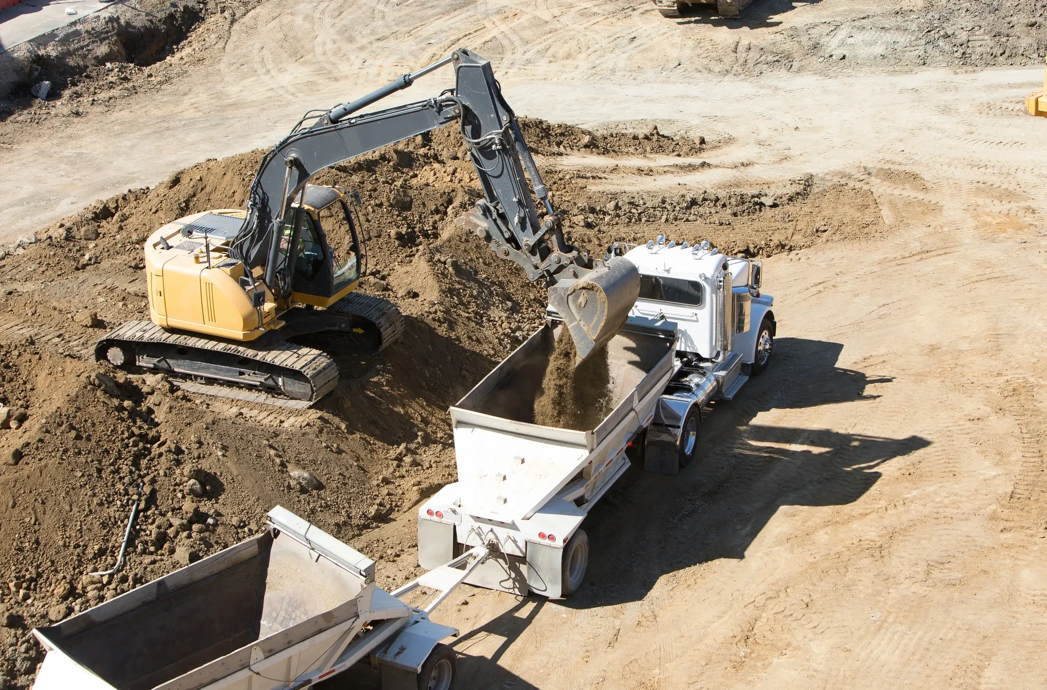 Excavator loading dump truck on job site
